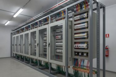 Sala de painéis elétricos industriais de baixa tensão com quadros de distribuição e bandejas de cabos organizadas